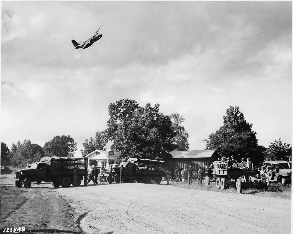 Red Army bombers dropping flour bombs on Blue Army troops and Addison&#x27;s Store during the Battle of Mount Carmel. Note the traffic congestion on the roadway. (Robertson Collection)