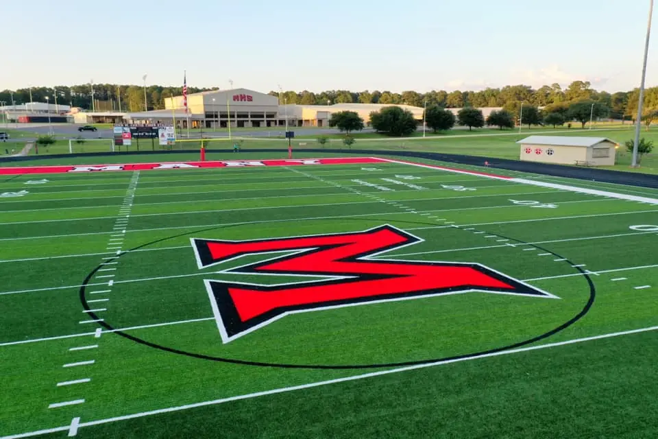 Photograph from the Facebook post “Many High football field, with school in the background”